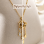 Gold necklace with a rose-shaped pendant and dangling teardrop charms, displayed on a beige jewelry bust. Arabic text is overlaid near the top.