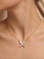 Gold necklace with a butterfly pendant worn by a person against a neutral background