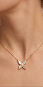 Gold necklace with a butterfly pendant worn by a person against a neutral background