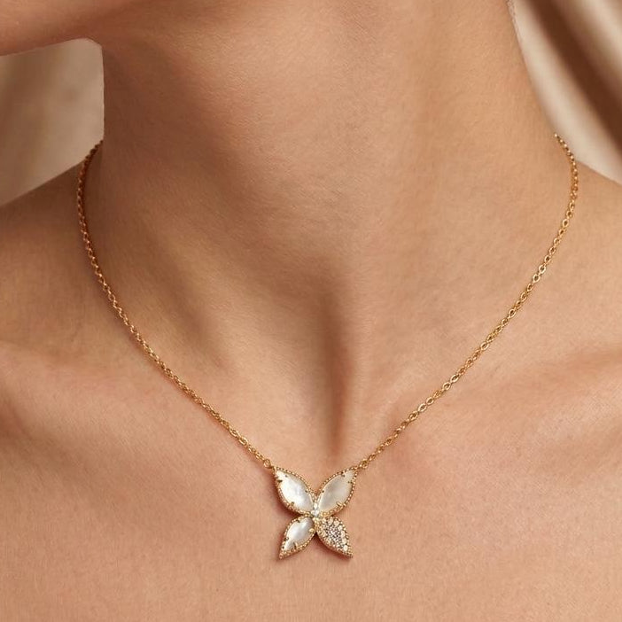 Gold necklace with a butterfly pendant worn by a person against a neutral background
