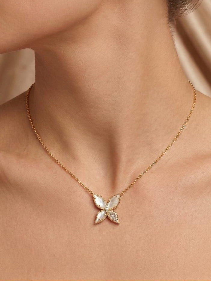 Gold necklace with a butterfly pendant worn by a person against a neutral background